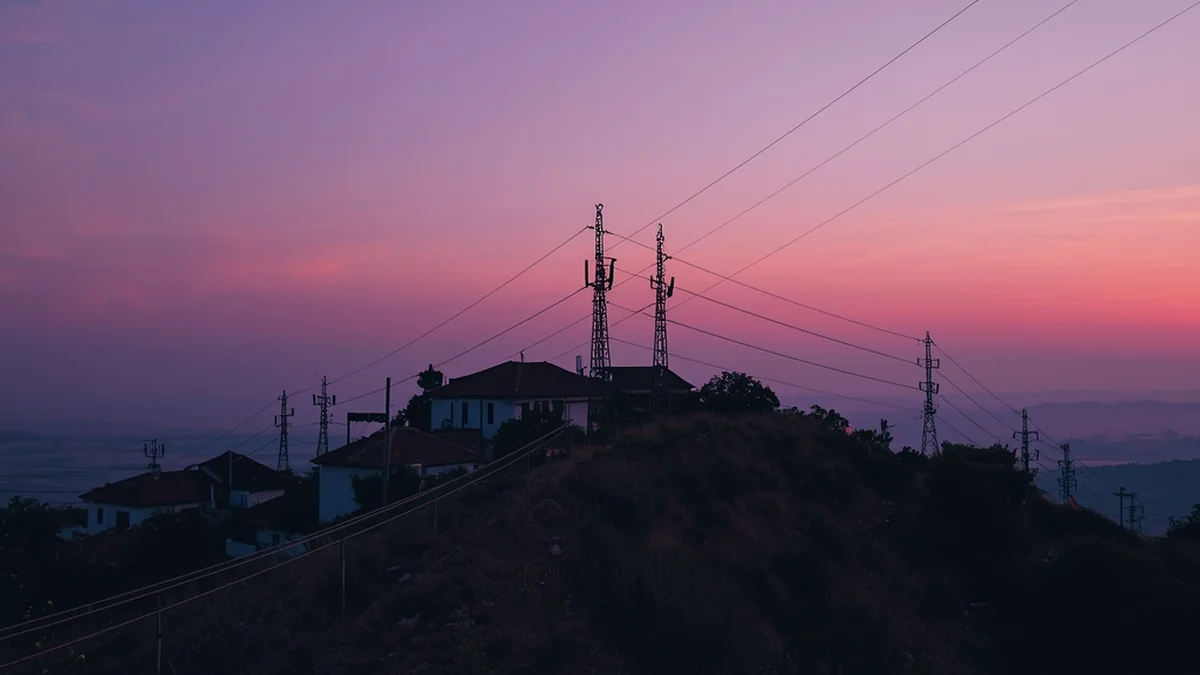 Repetitori i vodovi na brdu u sumrak – ilustracija elektromagnetnih polja u prostoru.