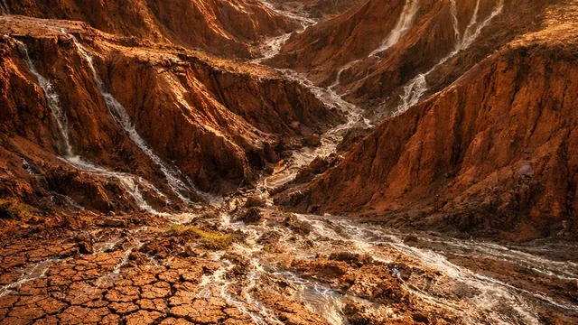 Duboke brazde erozije usečene u suvo crvenkasto zemljište — posledica gubitka zaštitnog pokrivača i površinskog spiranja.